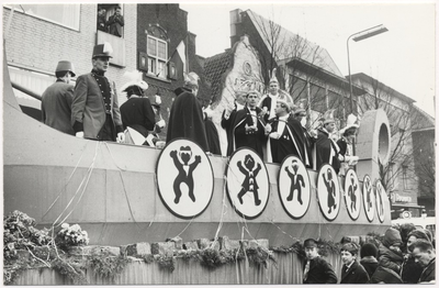 Carnaval 1965. Optocht . De Prinsenwagen op de Markt, gezien in de richting Veestraat. Op de wagen o.a. Prins Huub I. Harry Tops, Dhr.Ditks, en Guido van Thiel