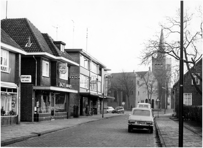 Kapelstraat, gezien in de richting R.K. kerk H. Lambertus, met links de winkels: kapper De Greef, Bazelmans, Rijnders en chinees-restaurant Lotus