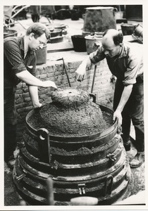 Harrie van der Steen en Lowie Loomans bij de productie van een klok, bezig met het gieten van een klok bij Eijsbouts